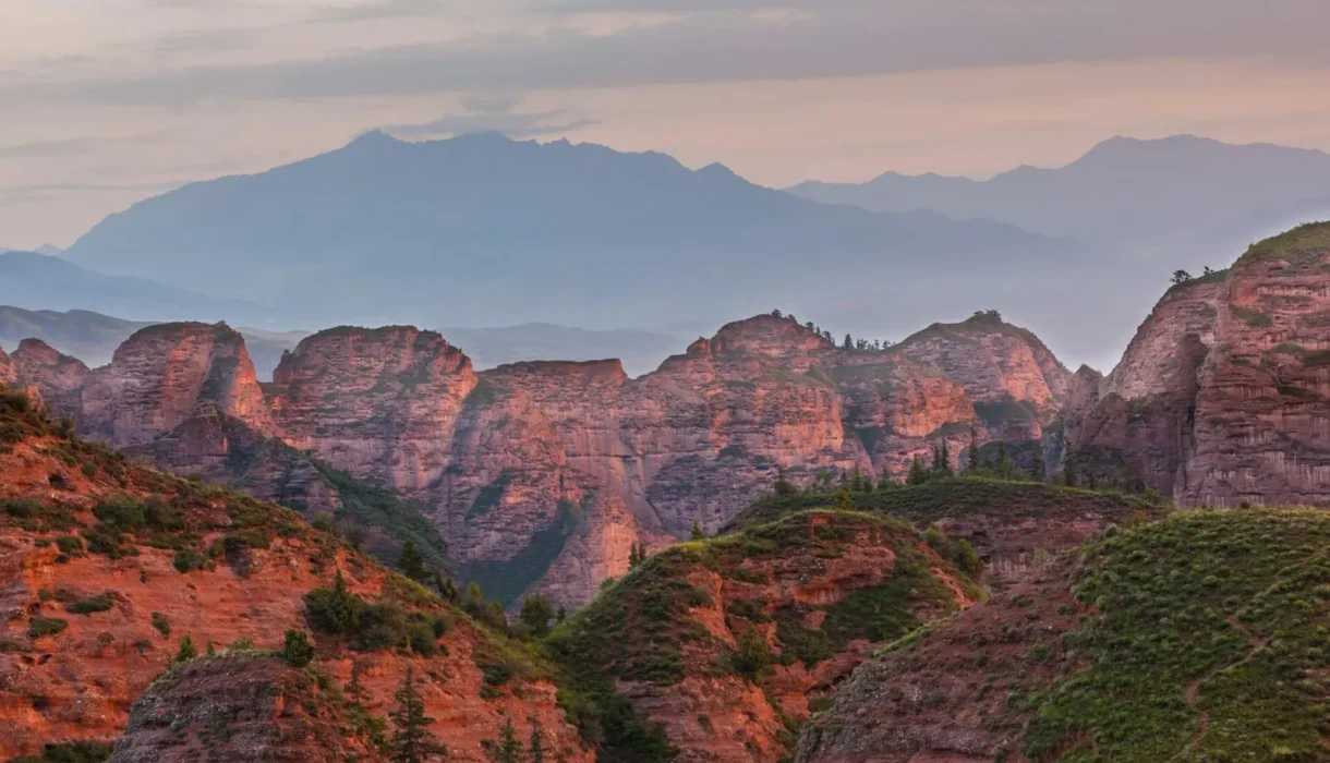 Red rock mountains at dusk with hazy peaks behind