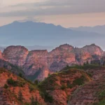 Red rock mountains at dusk with hazy peaks behind