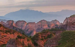 Red rock mountains at dusk with hazy peaks behind